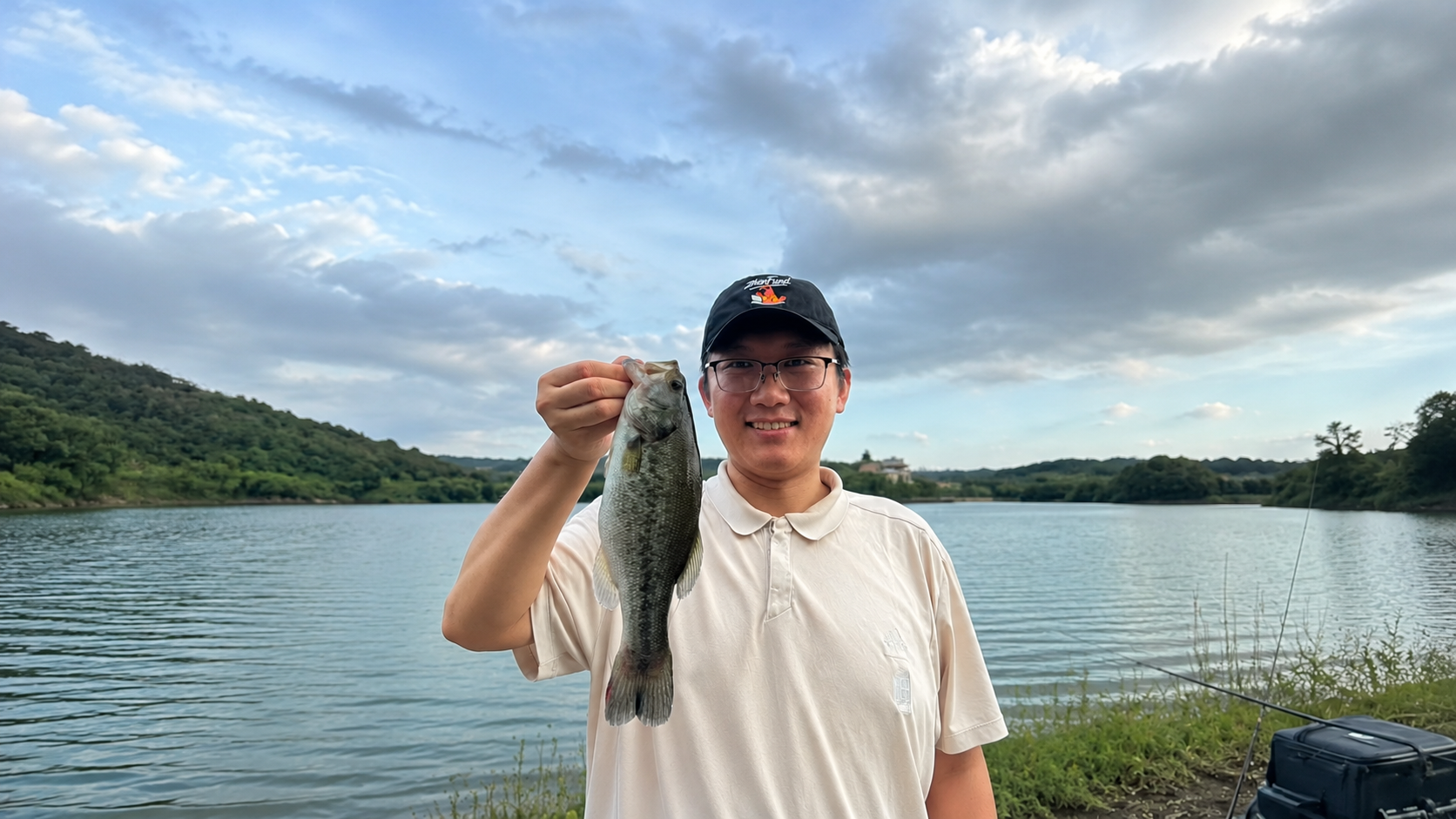 William Liu holding a fish by the lake